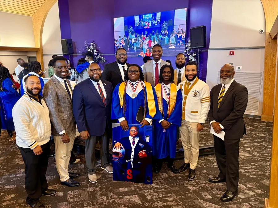 Graduating students in caps and gowns with brothers of Epsilon Beta Lambda Chapter.