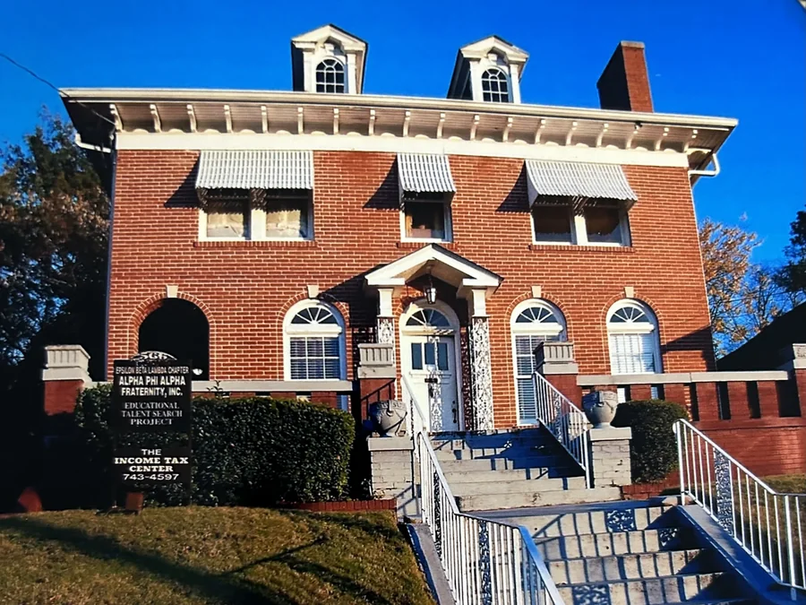 The Fraternity House: a three-storey red brick house with a bracketed cornice, two pedimented dormers, arched fanlight windows, and a white pedimented porch over the front door, above a flight of steps.