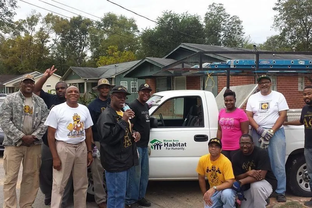 Brothers standing with a Habitat for Humanity truck outside a house.