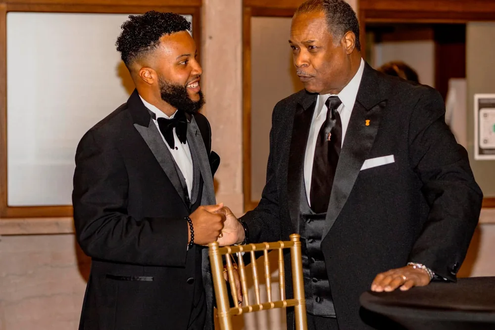 Two brothers in black tie greeting one another at a chapter event.